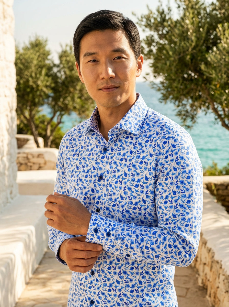 The Masutto Men's Button-Down Dress Shirt features a vibrant blue floral print across a premium white cotton fabric. This tailored shirt includes a refined spread collar, dark navy contrast buttons, and double-button cuffs, blending contemporary Italian s