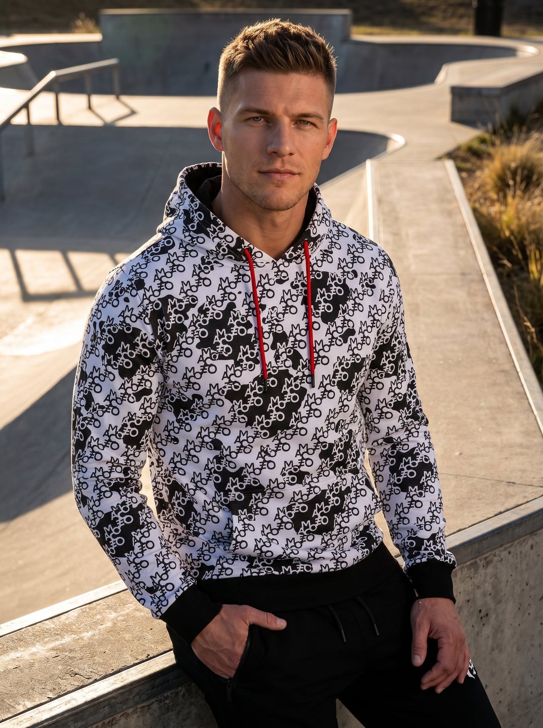 This bold men's hoodie features an all-over monochrome typographic and abstract print, accented by vibrant red drawstrings. Designed for a modern, athletic fit, it includes black ribbed cuffs and waistband, providing a striking streetwear aesthetic with h