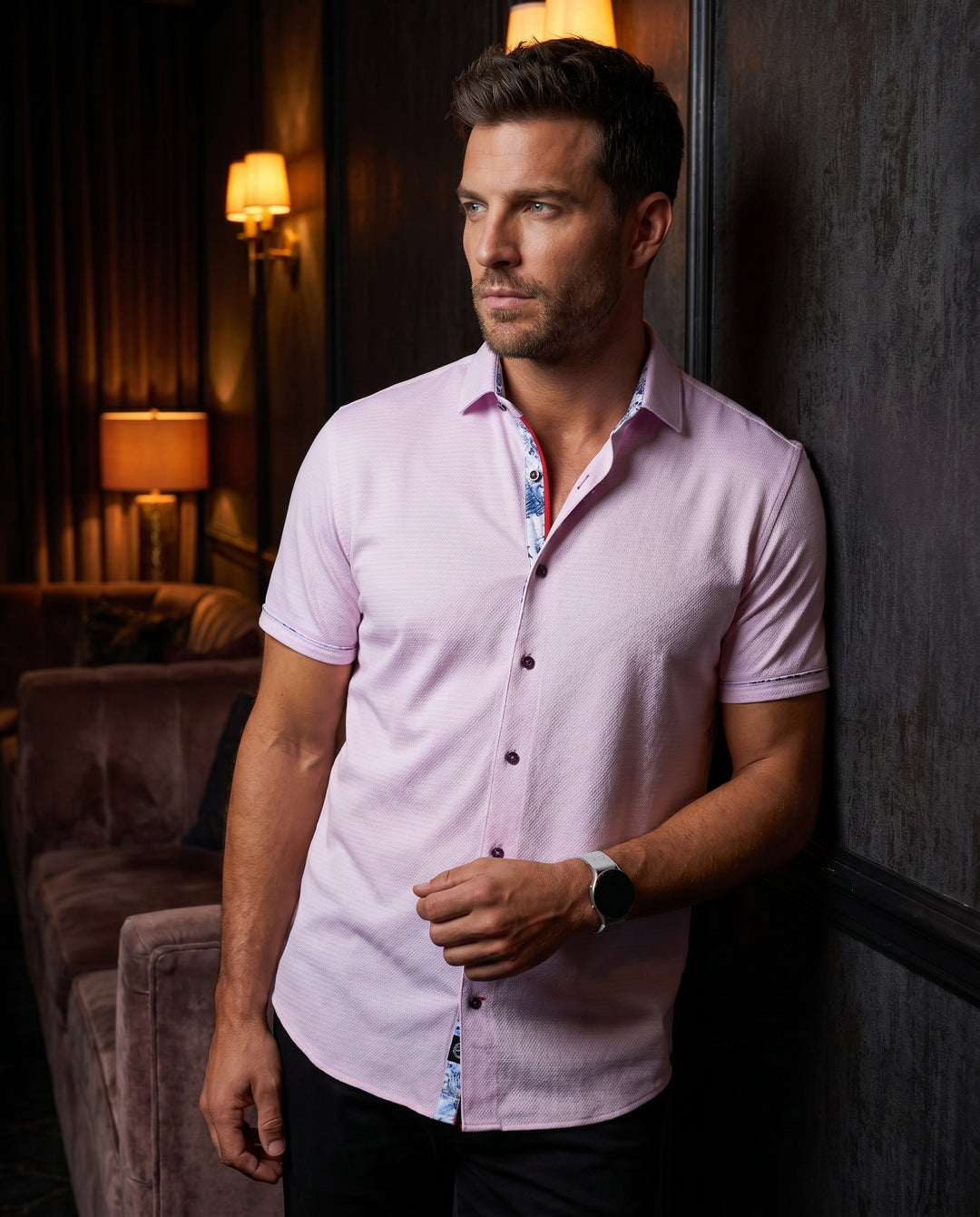 This tailored light pink short-sleeve button-down shirt features a subtle textured knit. It is accented by a sophisticated floral print inside the collar and placket, offering a modern twist on a classic silhouette for a refined yet casual look.