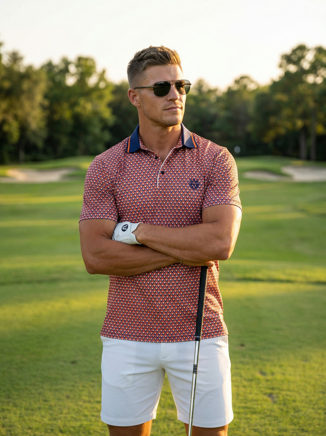This performance-fit polo features a vibrant geometric mosaic print in orange, navy, and white. The design includes a solid navy collar with orange tipping, a two-button placket, and a left chest logo, perfect for keeping cool while looking sharp.