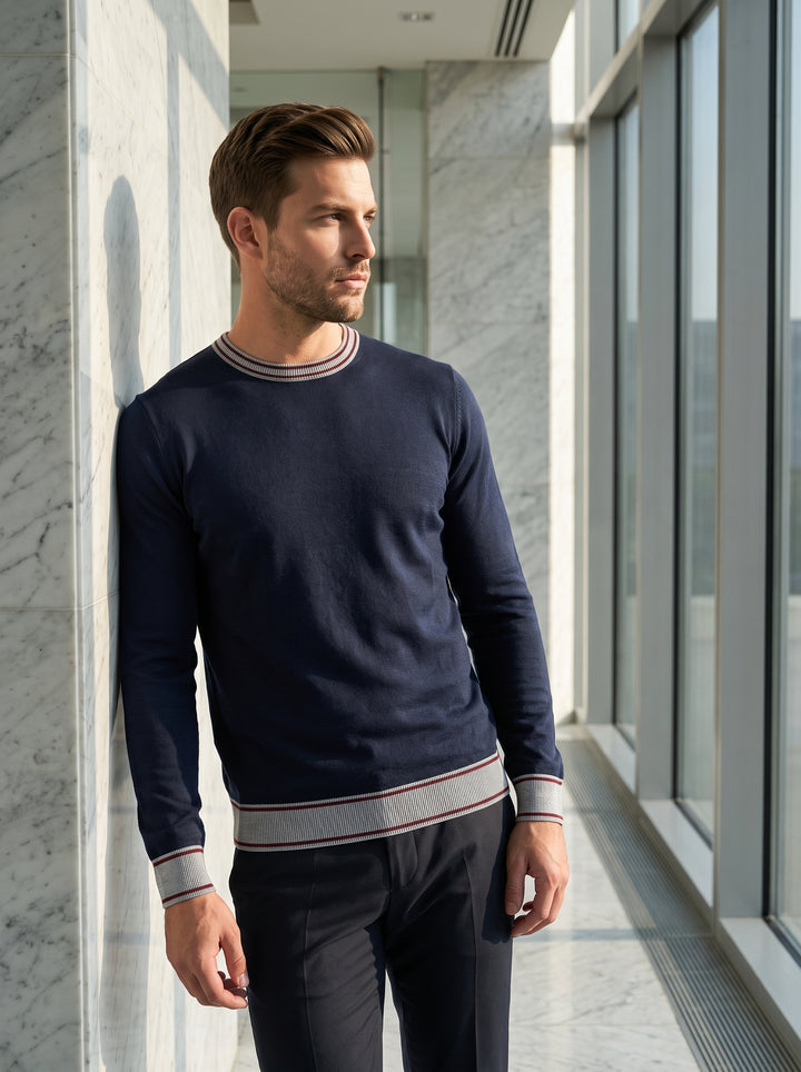 This navy blue long-sleeved sweater features a sophisticated crew neckline with grey and burgundy striped ribbing. The matching athletic-inspired striped cuffs and hem add a preppy, polished touch to the slim-fit silhouette, crafted from a smooth, fine-ga