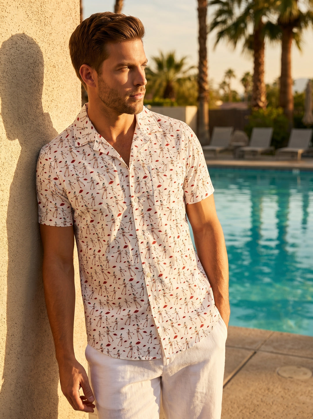 A crisp white short-sleeve button-down shirt featuring a whimsical, all-over pin-up girl and red lip print. The design includes a classic camp collar, a front chest pocket, and a curved hemline, offering a playful yet tailored summer aesthetic.