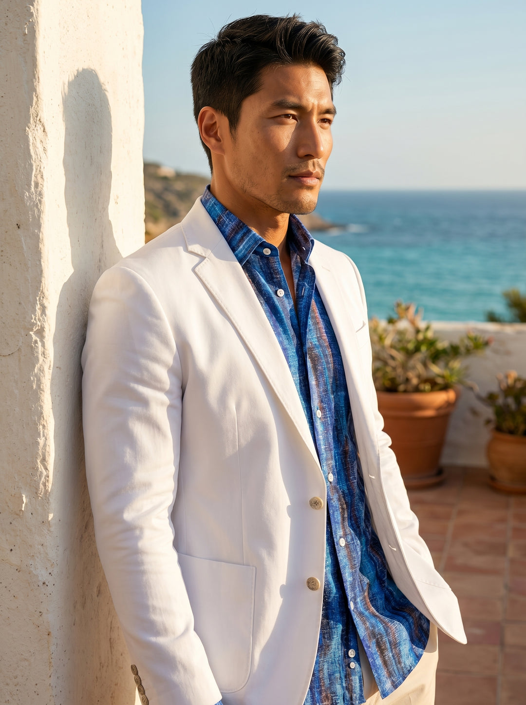 This tailored white blazer features a slim-fit silhouette with notch lapels and patch pockets, paired with a vibrant blue abstract print button-down shirt. The ensemble offers a crisp, summer-ready aesthetic ideal for elevated warm-weather occasions and s