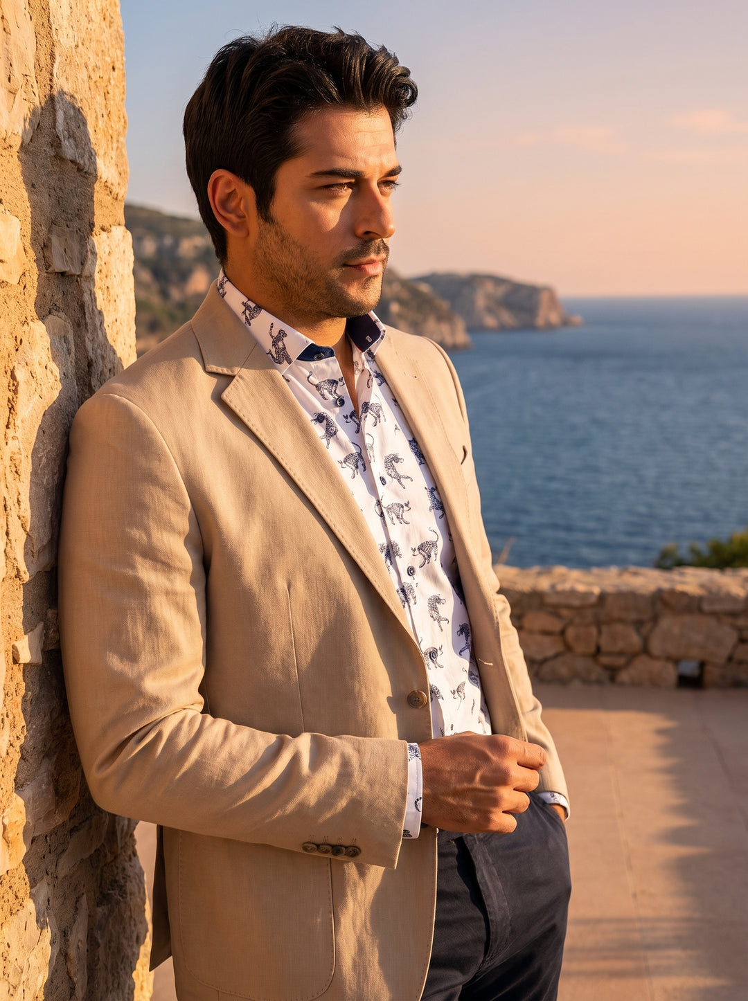 This tailored beige blazer features a slim fit and notched lapels, paired with a white button-down shirt featuring a navy cheetah motif. The ensemble offers a sophisticated blend of classic tailoring and bold, modern patterns for a refined summer look.