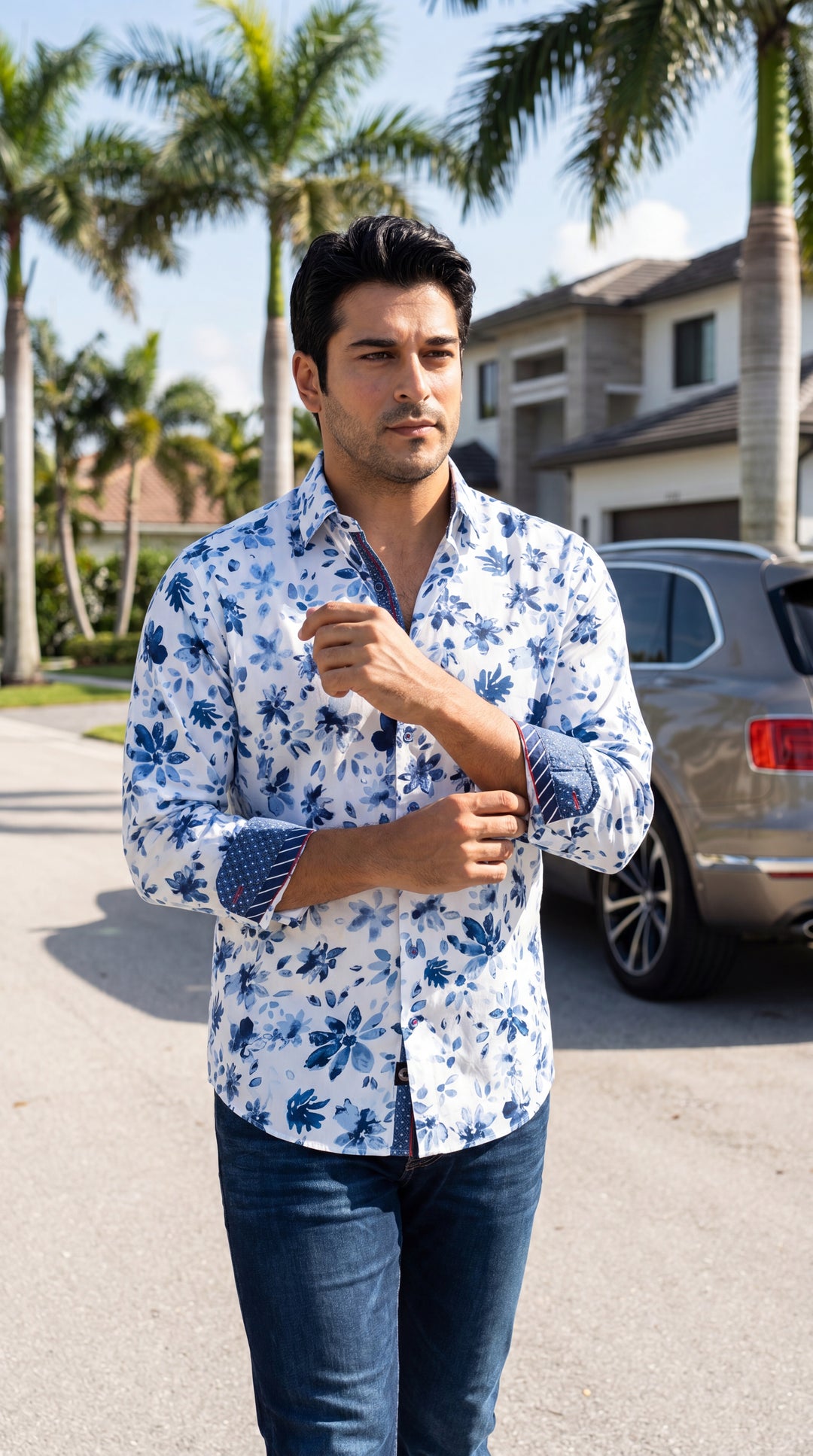 A sophisticated white button-down shirt featuring a vibrant blue floral print with artistic watercolor textures. The design includes contrasting patterned cuffs and inner collar accents, offering a tailored fit that pairs perfectly with denim for a refine