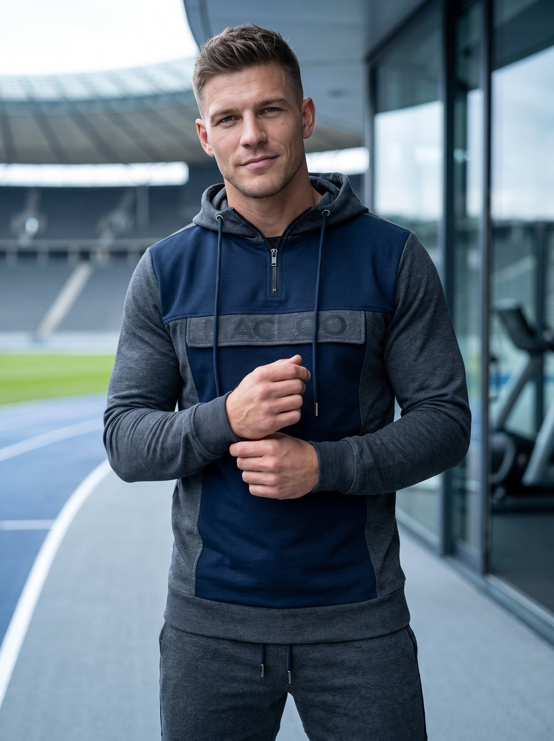 This premium athletic hoodie features a modern color-blocked design in charcoal grey and navy blue. Crafted with a quarter-zip neckline and adjustable drawstring hood, it includes a branded chest panel and ribbed cuffs for a functional yet stylish athleti