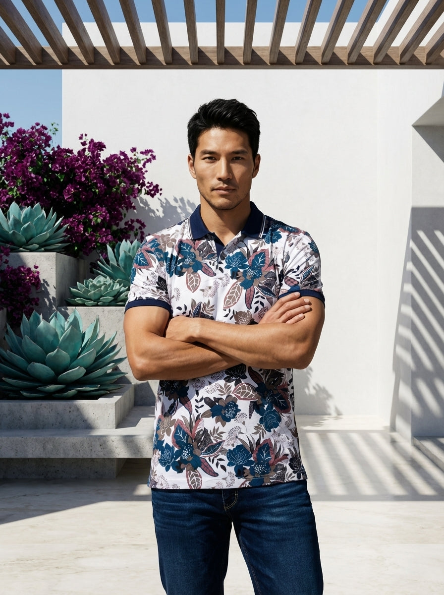 This men's short-sleeve polo features a vibrant white base adorned with a sophisticated navy, teal, and mauve floral motif. It includes a contrasting solid navy ribbed collar and sleeve cuffs, finished with a classic three-button placket for a refined loo