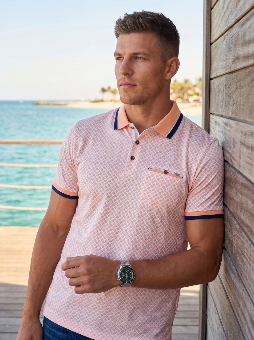 This stylish peach-toned polo shirt features an intricate geometric micro-print and contrasting navy blue collar accents. Designed with a short-sleeved silhouette, it includes a functional chest pocket and a three-button placket, perfect for a refined yet