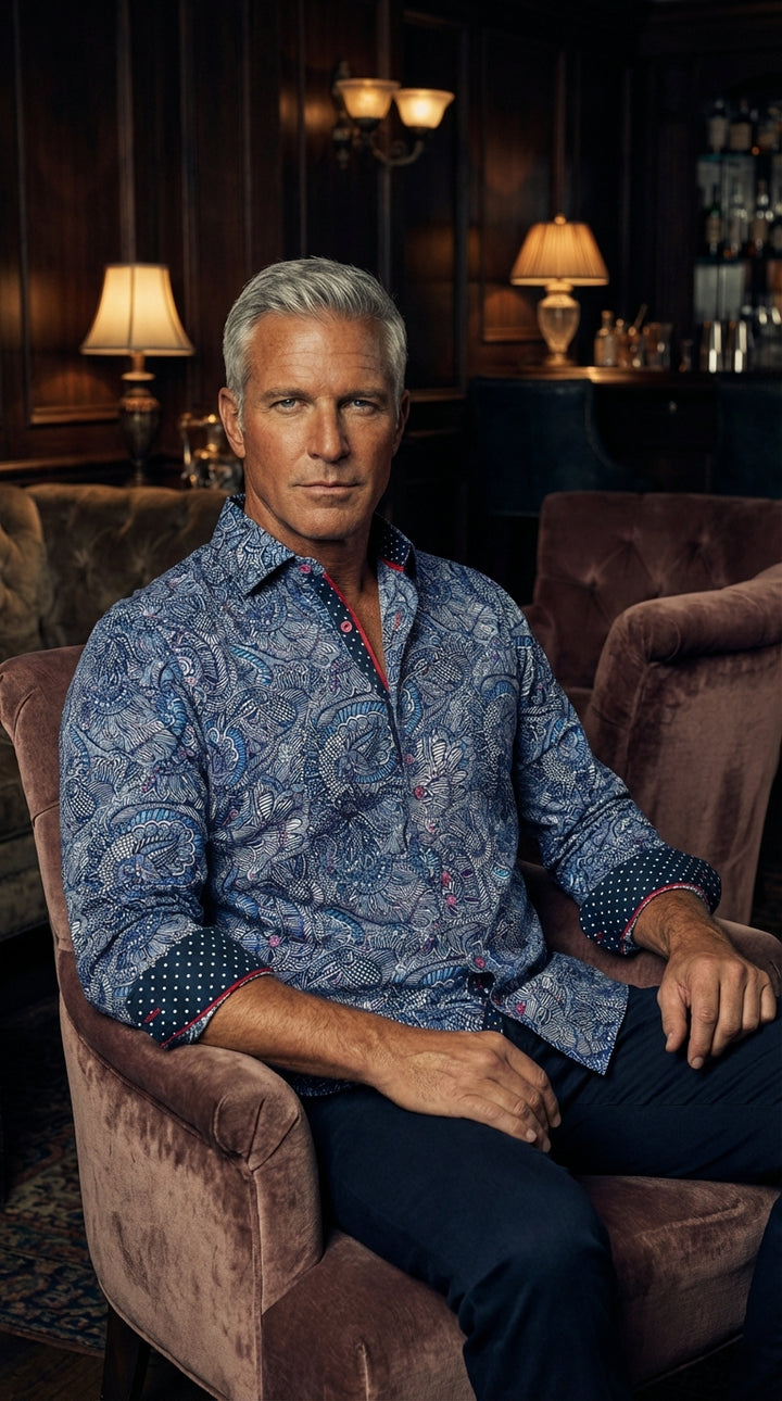 This premium long-sleeve shirt features a vibrant blue intricate paisley and floral print. It showcases unique contrasting navy polka-dot cuffs and collar lining with red piping. Crafted for style, it offers a modern tailored fit perfect for upscale socia
