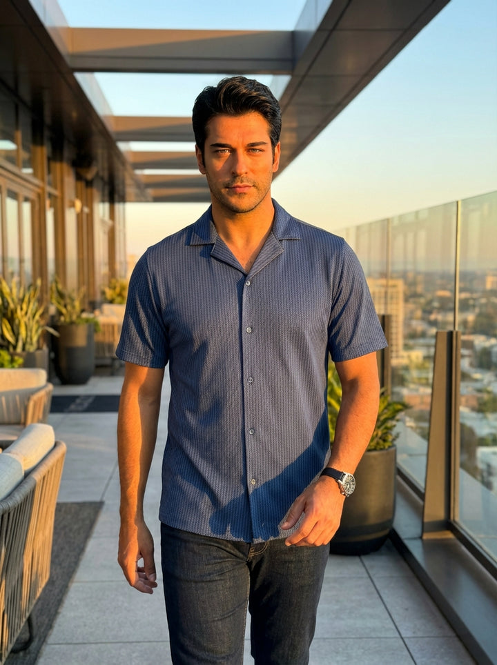 Elevate your casual wardrobe with this short-sleeved blue button-down shirt featuring a refined diagonal herringbone pattern. Designed with a classic camp collar and tailored fit, this sophisticated piece offers a modern silhouette perfect for layering or