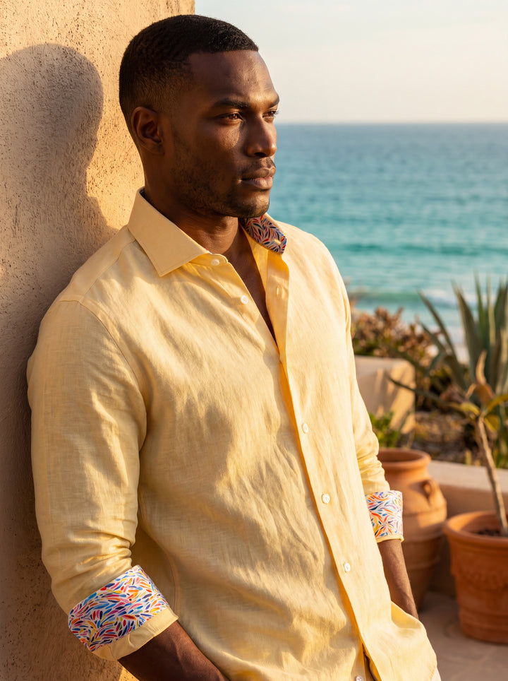 This pale yellow long-sleeve dress shirt features a textured linen-blend fabric and a classic spread collar. A vibrant, multi-colored abstract print lines the interior collar and cuffs, adding a playful, sophisticated detail to this refined Masutto button