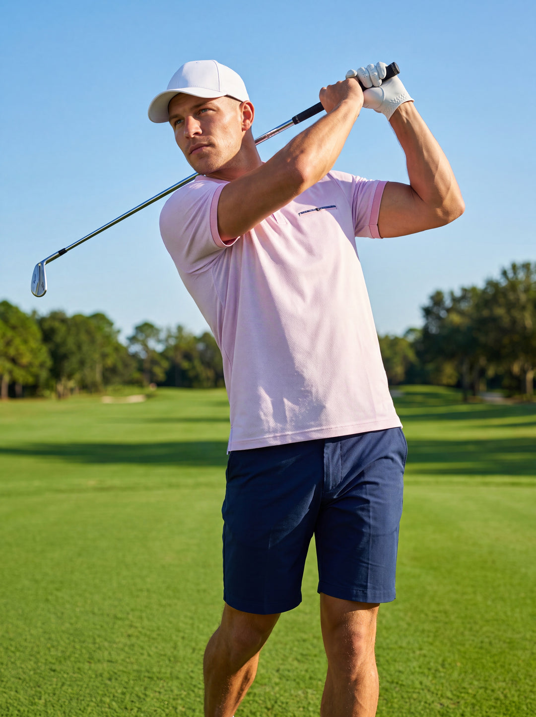 This light pink polo shirt features a navy blue contrast collar and a subtle pattern. It is designed with a short sleeve cut, a decorative chest welt, and a three-button placket, offering a modern tailored fit for casual elegance.