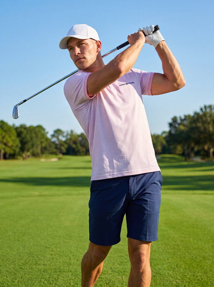 This light pink polo shirt features a navy blue contrast collar and a subtle pattern. It is designed with a short sleeve cut, a decorative chest welt, and a three-button placket, offering a modern tailored fit for casual elegance.