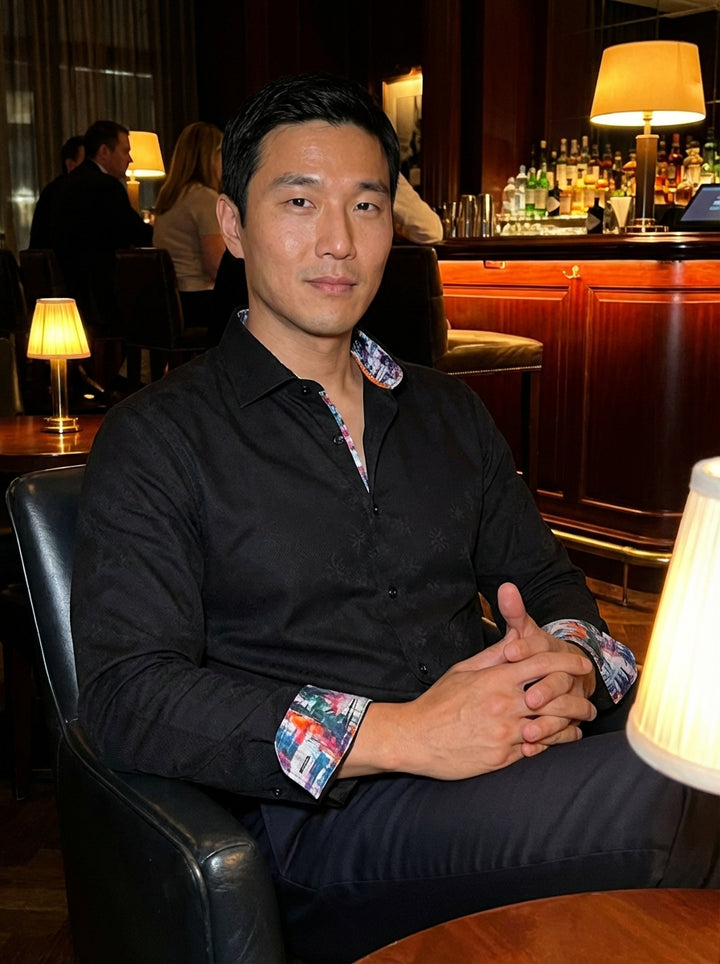 This sophisticated black Masutto dress shirt features a subtle tone-on-tone jacquard floral pattern. The classic silhouette is elevated by vibrant, multi-colored artistic lining along the collar and cuffs, adding a modern, hidden flair to a sharp, profess