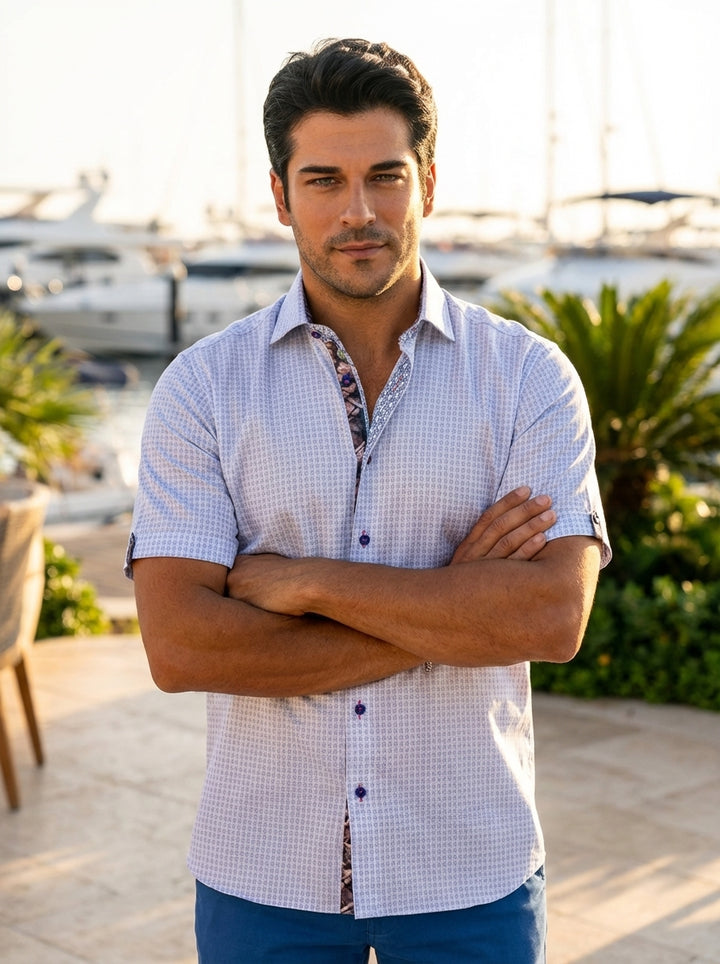 A sophisticated light blue short-sleeve button-down shirt featuring a delicate geometric micro-print throughout. Contrast patterned inner placket and collar detailing add a modern touch, while navy buttons with pink stitching provide a refined pop of colo