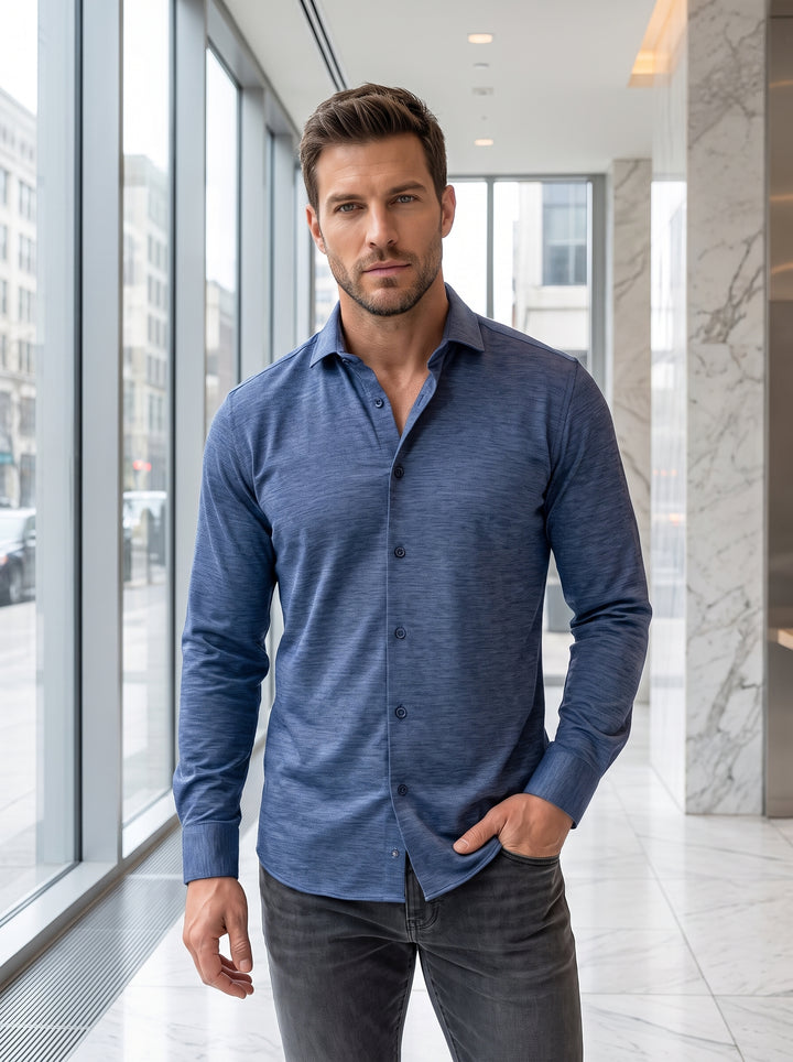 This sophisticated men's long-sleeve button-down shirt features a unique heathered indigo texture. Crafted for versatility, it offers a tailored fit with a classic spread collar and adjustable cuffs, blending the comfort of knitwear with the sharp look of