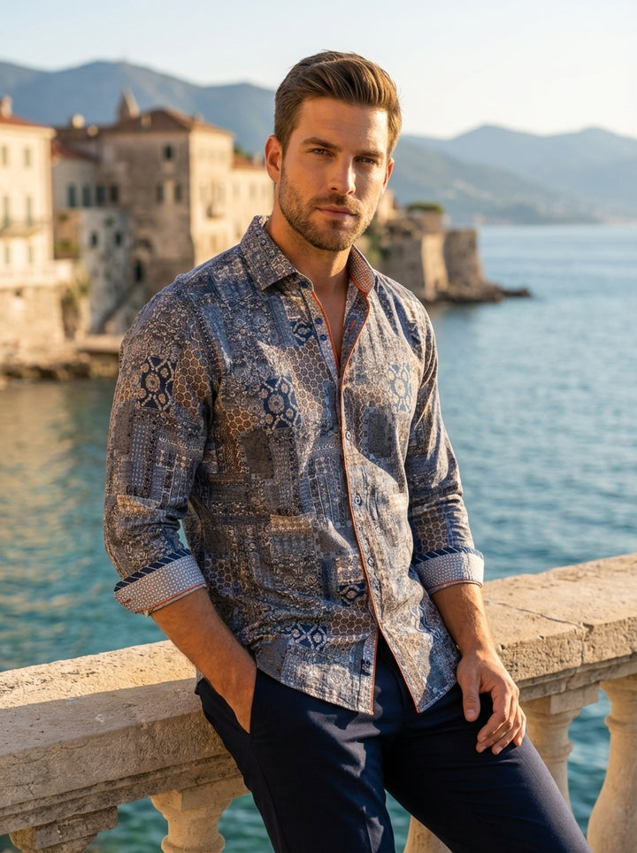 This men's long-sleeve button-down features an intricate patchwork print in shades of blue, grey, and bronze. Crafted with a tailored fit, it includes contrasting orange piping along the placket and patterned inner cuffs for a sophisticated, modern aesthe