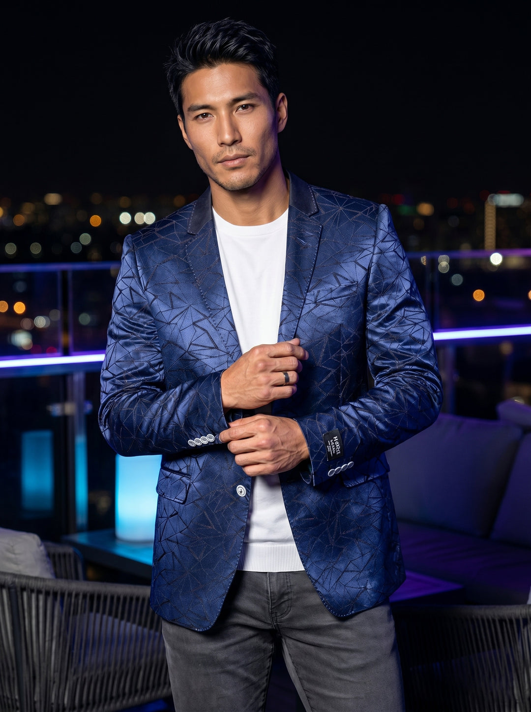 This striking blue blazer features a metallic sheen and an intricate, geometric shattered-glass pattern. Designed with a slim fit, notched lapels, and a contrasting collar detail, it is a statement piece for the modern man seeking a bold, artistic aesthet