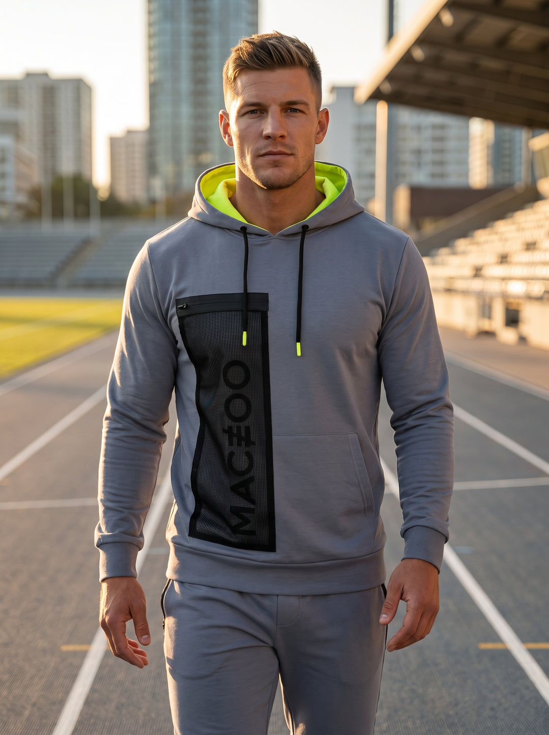 This modern men's athletic hoodie in slate grey features a bold neon yellow lining and matching drawstring aglets. A vertical mesh pocket with a zip closure and 'MACEOO' branding adds a functional, technical edge to this sleek performance piece.