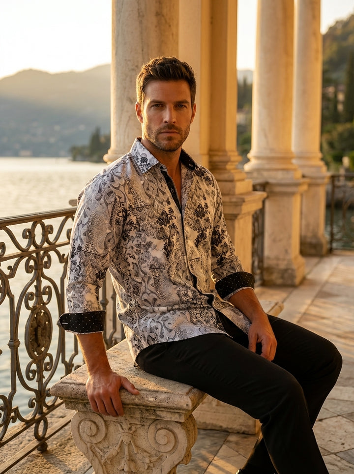 This men's button-down shirt features an intricate black damask and paisley print over a white and light gray background. It includes contrasting black patterned inner cuffs and a matching collar stand for a sophisticated, modern, and high-contrast look.