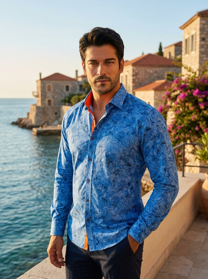 This premium men's button-down shirt features a vibrant blue intricate paisley and floral print. The tailored design includes a contrasting orange inner collar stand and matching button stitching, creating a sophisticated yet bold aesthetic for the modern