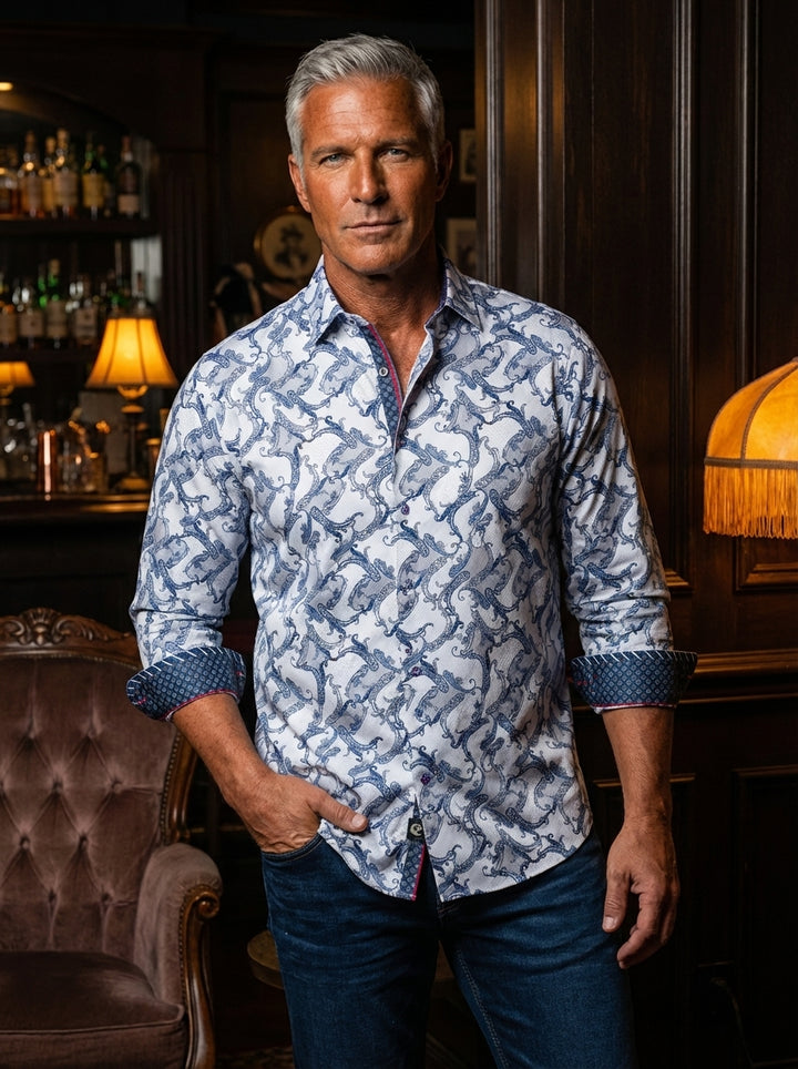 This premium long-sleeved button-down shirt features an intricate blue swirling baroque print against a crisp white base. Designed with a tailored fit, it showcases contrast geometric inner cuffs and red piping details, offering a sophisticated edge for m