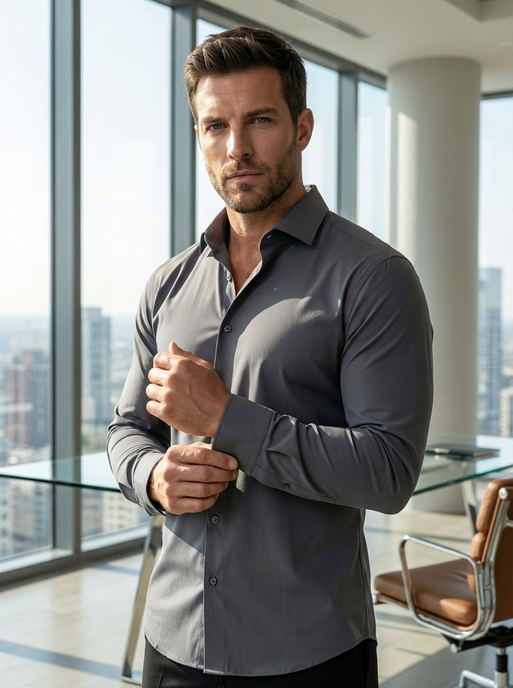 This men's long-sleeve dress shirt in charcoal grey features a streamlined, slim-fit silhouette crafted from high-performance, moisture-wicking stretch fabric. It includes a classic spread collar, button-front closure, and structured cuffs, offering a mod