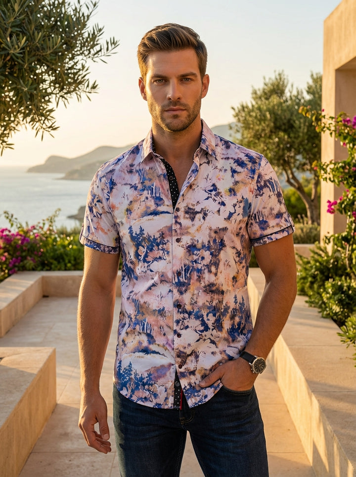This men's short-sleeve button-down features a vibrant, painterly landscape print in shades of indigo, peach, and lilac. Crafted with a tailored fit, it includes a contrasting black polka-dot inner collar and placket detail for a sophisticated, modern tou