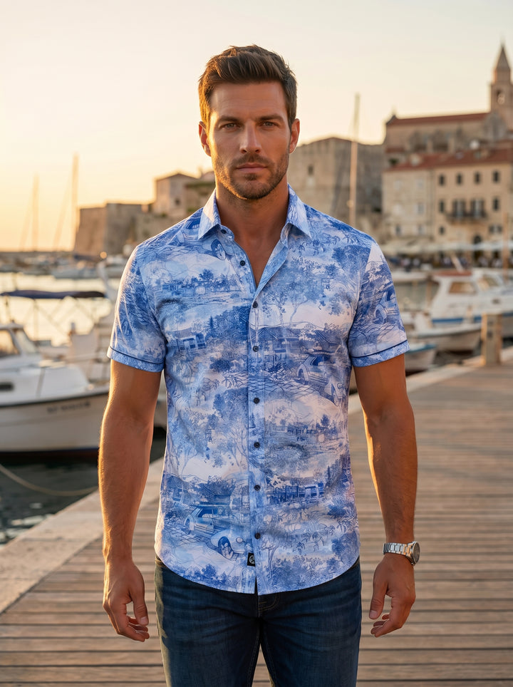 This men's short-sleeved button-up shirt features a vibrant blue and white toile-inspired print depicting scenic landscapes and classic cars. Crafted from breathable fabric, it offers a slim fit, structured collar, and contrasting button details for a sop