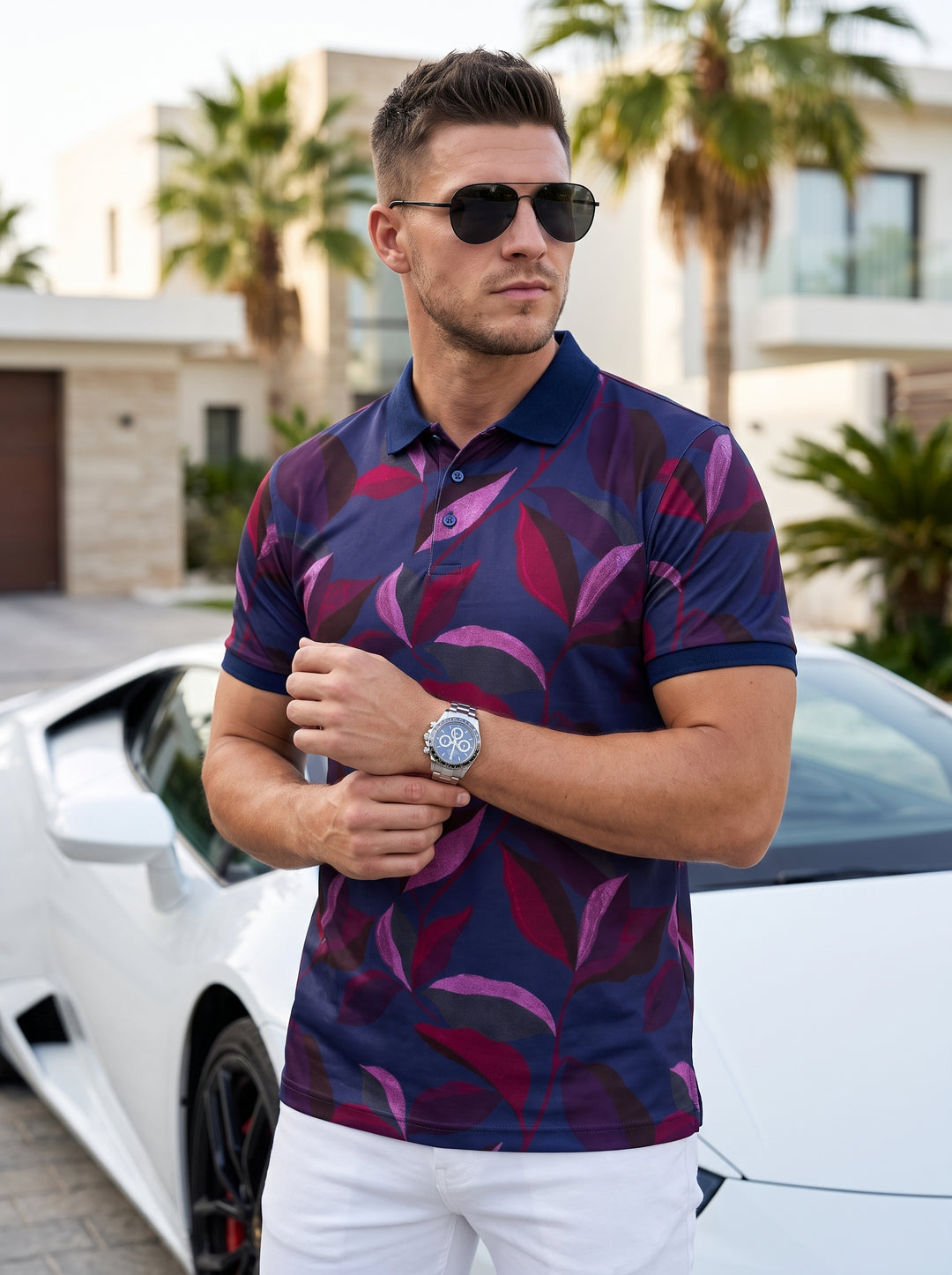 This men's short-sleeve polo shirt features a vibrant all-over botanical leaf print in shades of plum, magenta, and charcoal against a navy blue base. It is designed with a classic ribbed collar, three-button placket, and a tailored, modern fit.