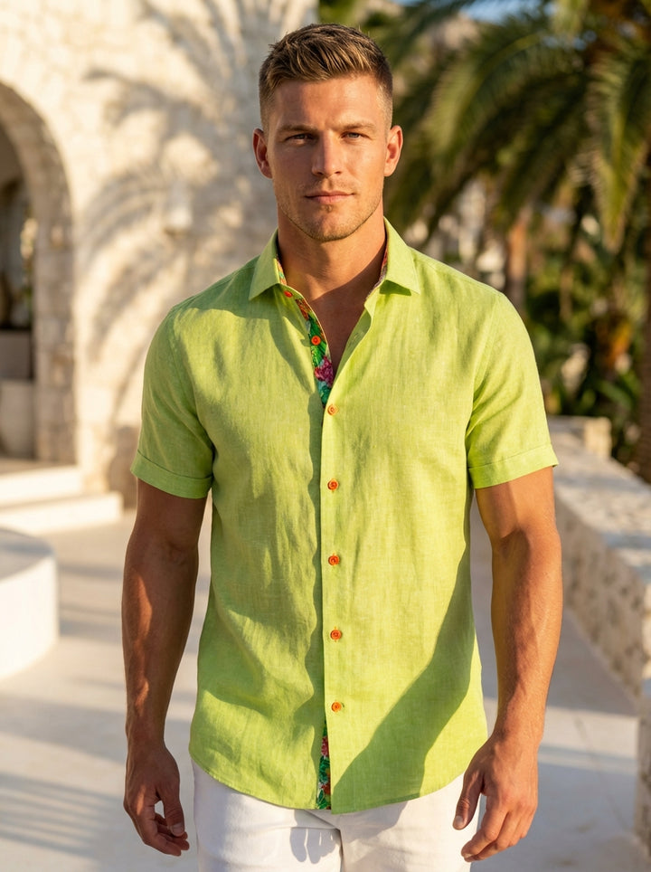 This Masutto short-sleeved shirt features a vibrant lime green linen-blend fabric with striking orange button details. The interior collar is lined with a colorful tropical floral print, offering a playful hidden detail that enhances its sophisticated yet