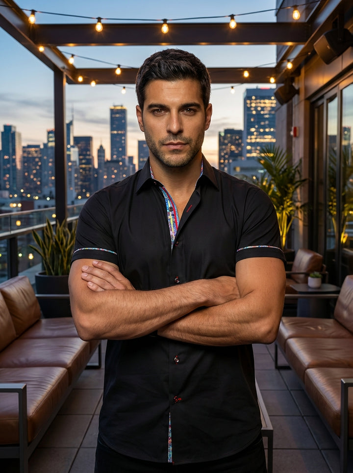 A sophisticated short-sleeve button-down shirt in premium black fabric. This modern fit garment features vibrant multi-colored interior collar detailing, decorative contrast piping on the sleeves, and stylish accent stitching, making it perfect for transi