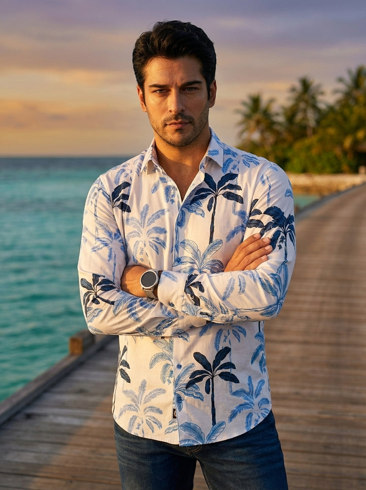 This men's long-sleeve button-down shirt features a crisp white base adorned with a sophisticated blue palm tree print. Crafted with a modern tailored fit, it offers a refined take on tropical motifs, blending casual island vibes with clean, structured li