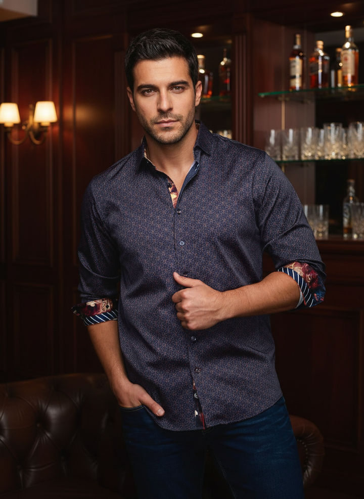 A sophisticated navy button-down featuring an intricate geometric starburst print. This tailored shirt is elevated by vibrant contrast-patterned cuffs and collar lining, blending classic craftsmanship with bold, modern detailing for a distinguished smart-