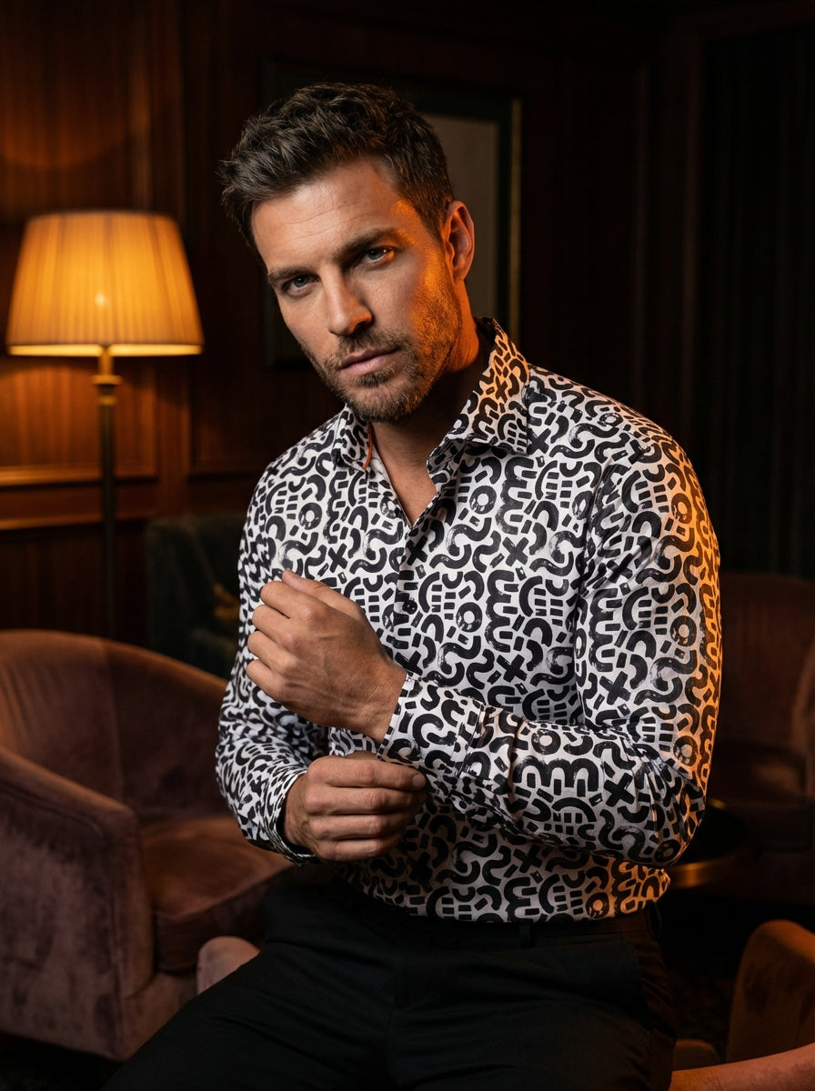 This Masutto men's long-sleeve button-down shirt features a bold, monochromatic abstract print. The design showcases black brushstroke-style symbols, including swirls and geometric shapes, against a crisp white fabric. It is finished with dark buttons and