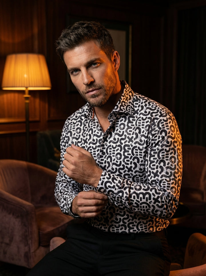 This Masutto men's long-sleeve button-down shirt features a bold, monochromatic abstract print. The design showcases black brushstroke-style symbols, including swirls and geometric shapes, against a crisp white fabric. It is finished with dark buttons and