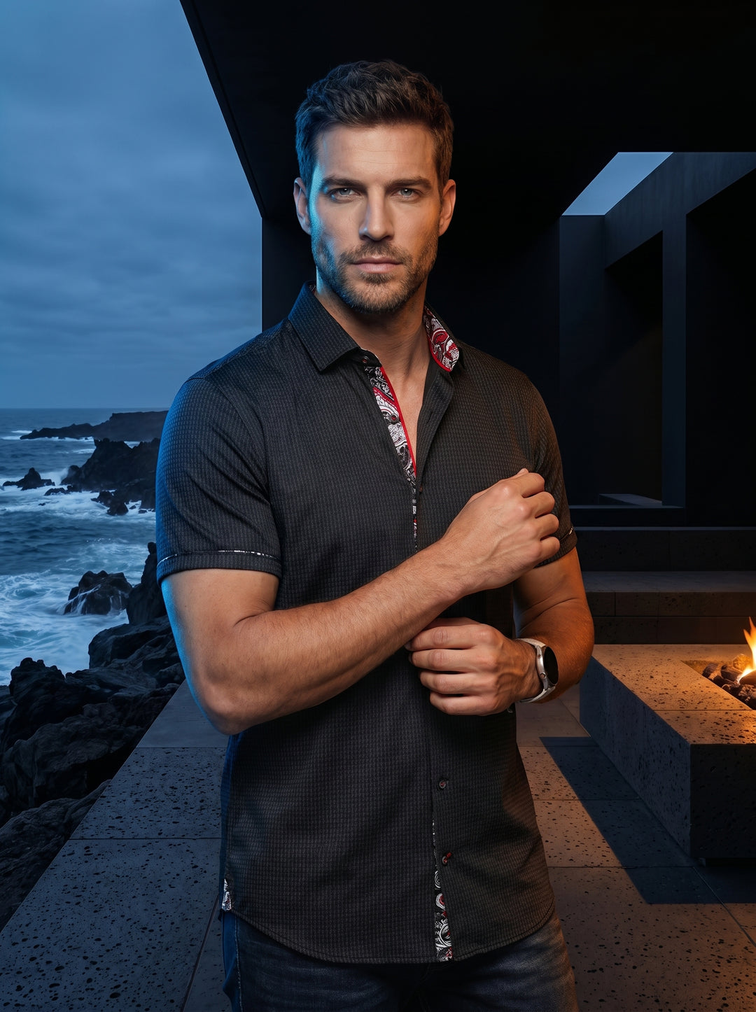 A sophisticated black short-sleeve button-down shirt featuring a subtle textured micro-pattern. It highlights intricate red and white paisley contrast lining along the inner collar and placket, offering a modern, tailored fit that blends edgy detail with 
