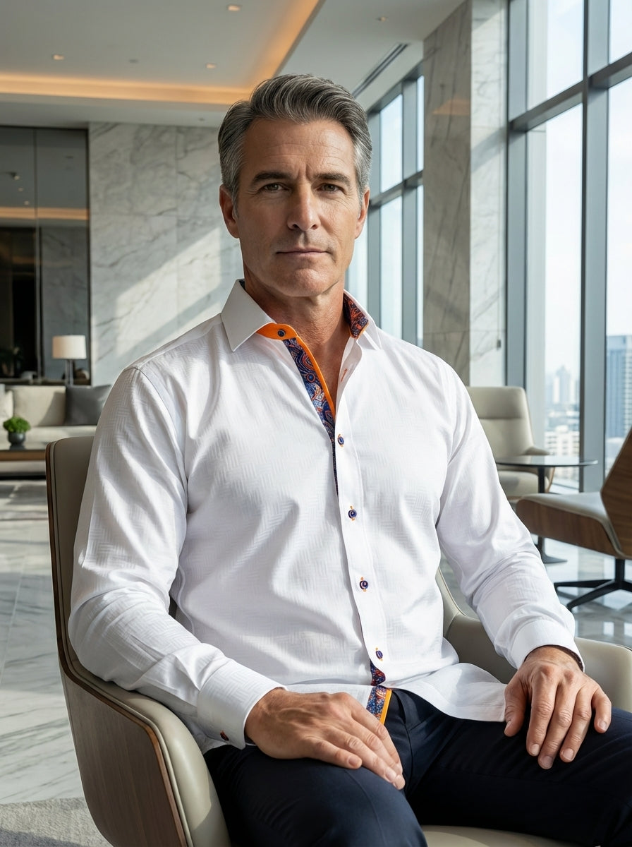 This white long-sleeve button-down features a subtle tonal geometric weave for texture. It is distinguished by vibrant orange inner collar lining, a paisley-patterned placket, and navy blue buttons with orange stitching, offering a sophisticated yet moder