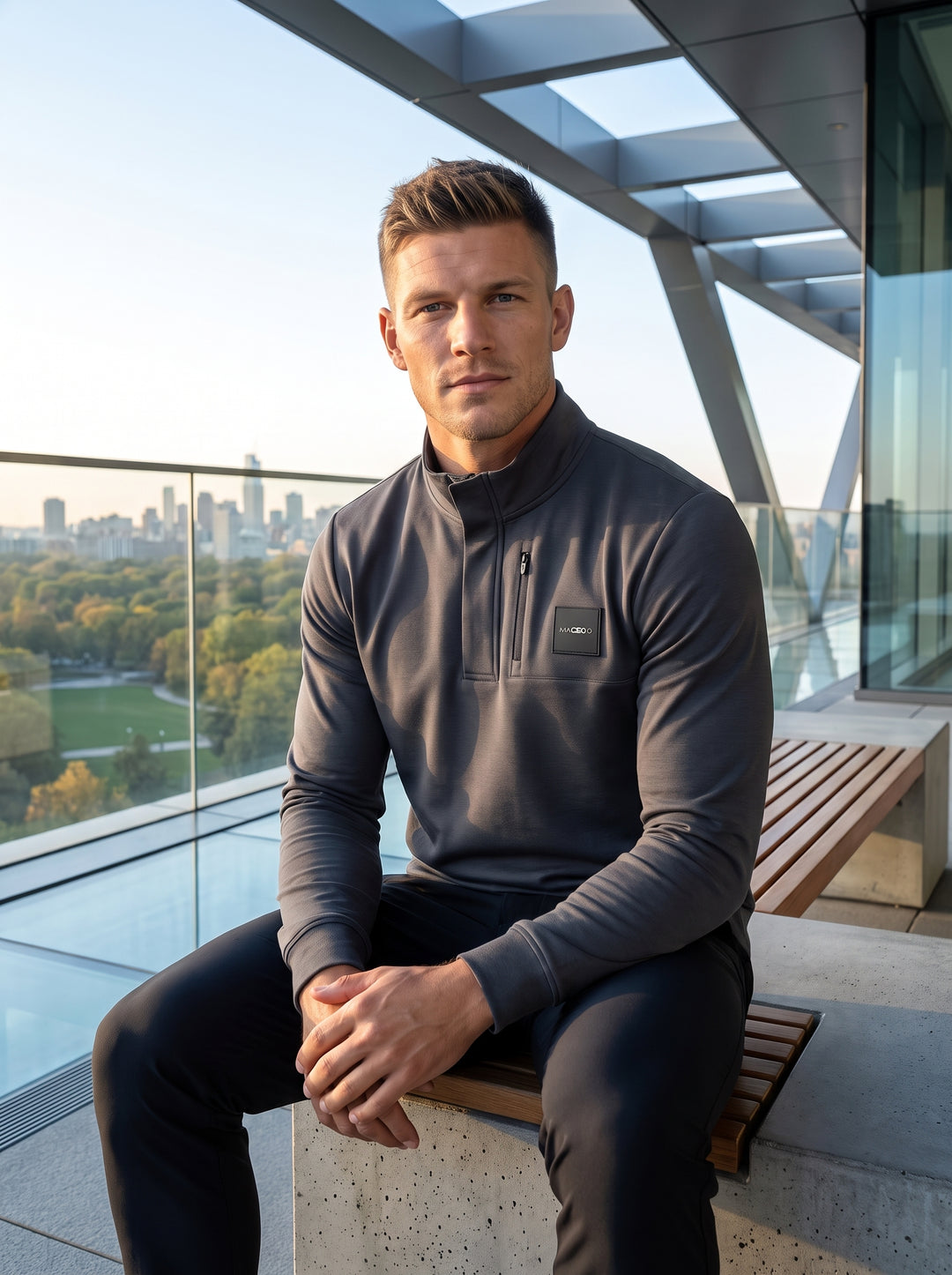 This sophisticated charcoal grey quarter-zip pullover features a clean, athletic fit with a structured mock collar and a concealed placket. It is accented with a sleek branded patch and a vertical zippered chest pocket, combining modern utility with premi