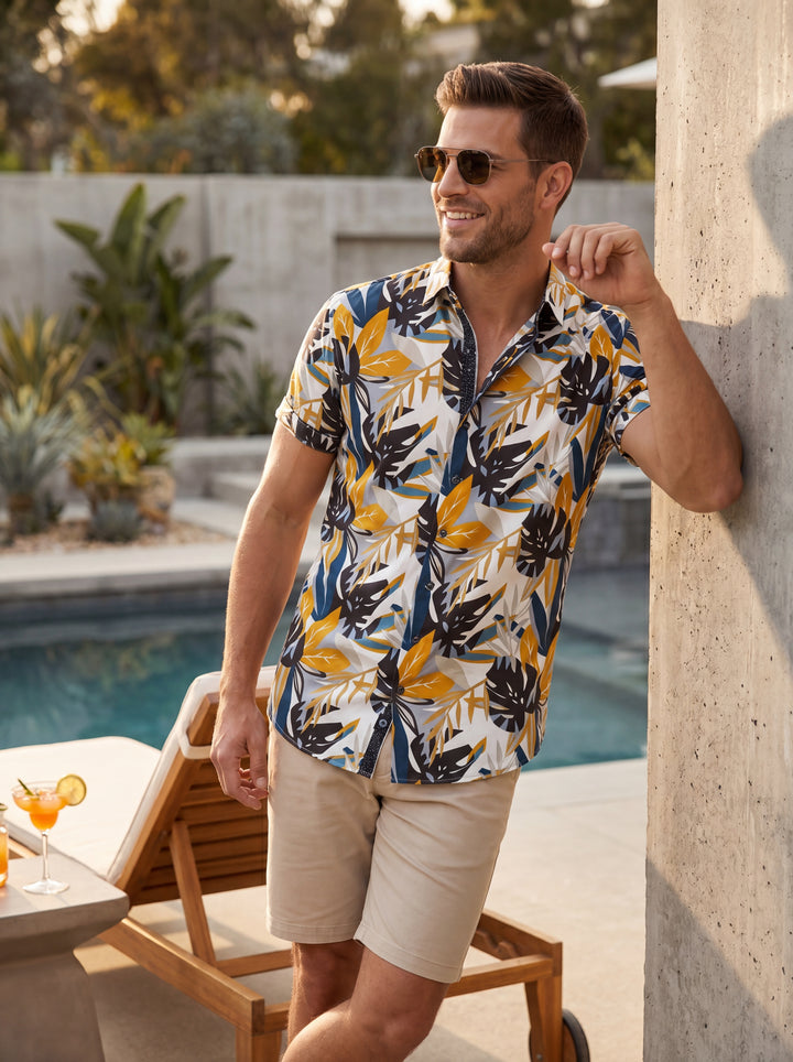 This men's short-sleeved button-down shirt features a bold tropical botanical print in a modern color palette of ochre yellow, deep navy, and grey. Its tailored fit and crisp collar make it a sophisticated choice for warm-weather adventures and vacations.