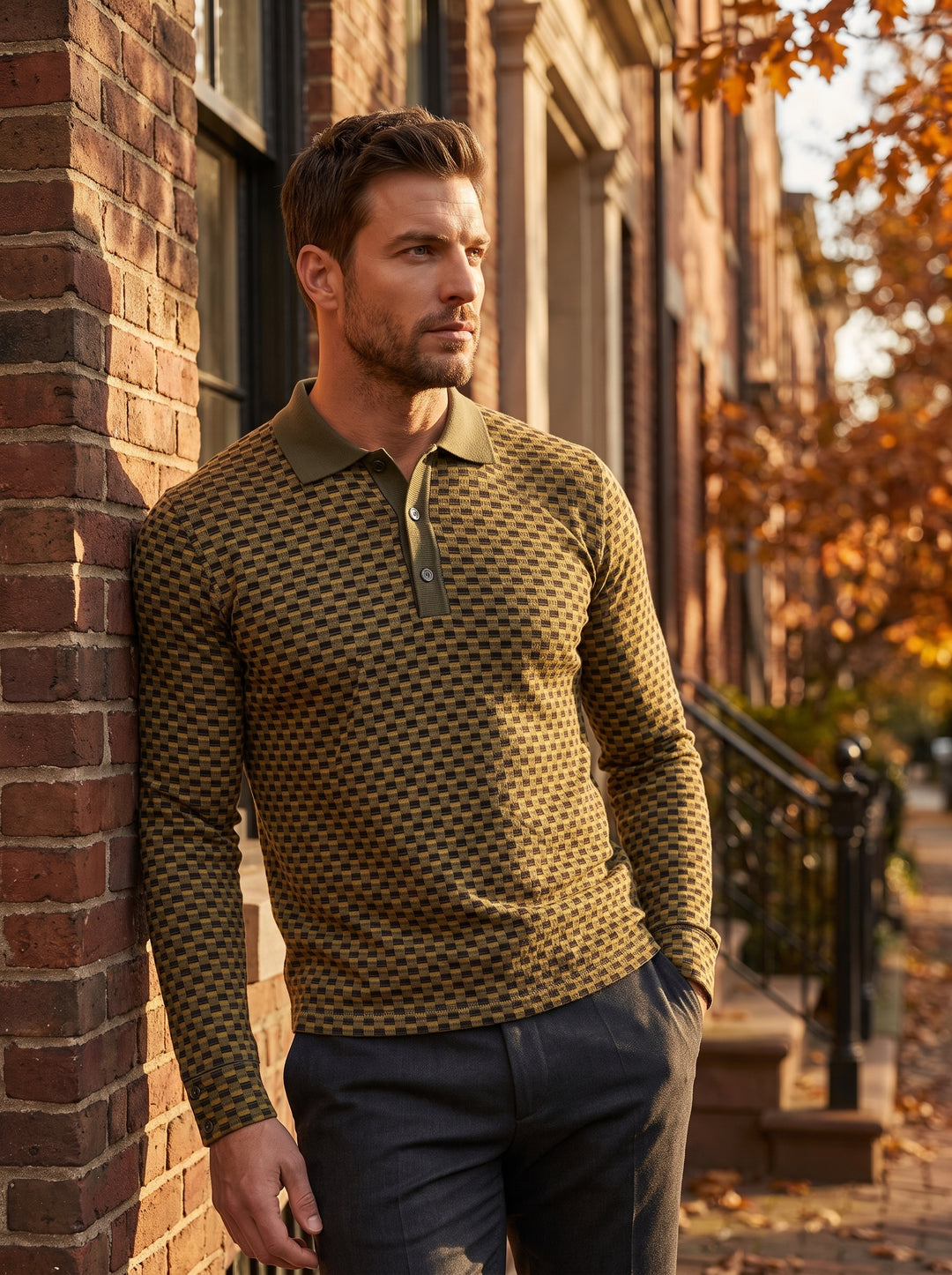 A long-sleeved polo shirt featuring a complex olive and gold checkered geometric pattern. It includes a ribbed olive green collar, a three-button placket, and buttoned cuffs, offering a sophisticated knit look with a slim, modern fit.