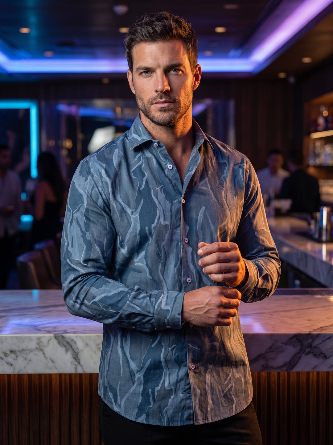 This men's long-sleeve button-down shirt features a sophisticated abstract camo-inspired pattern in various shades of blue and slate grey. Crafted with a tailored fit, it includes a classic spread collar, white contrast buttons, and a curved hem for versa