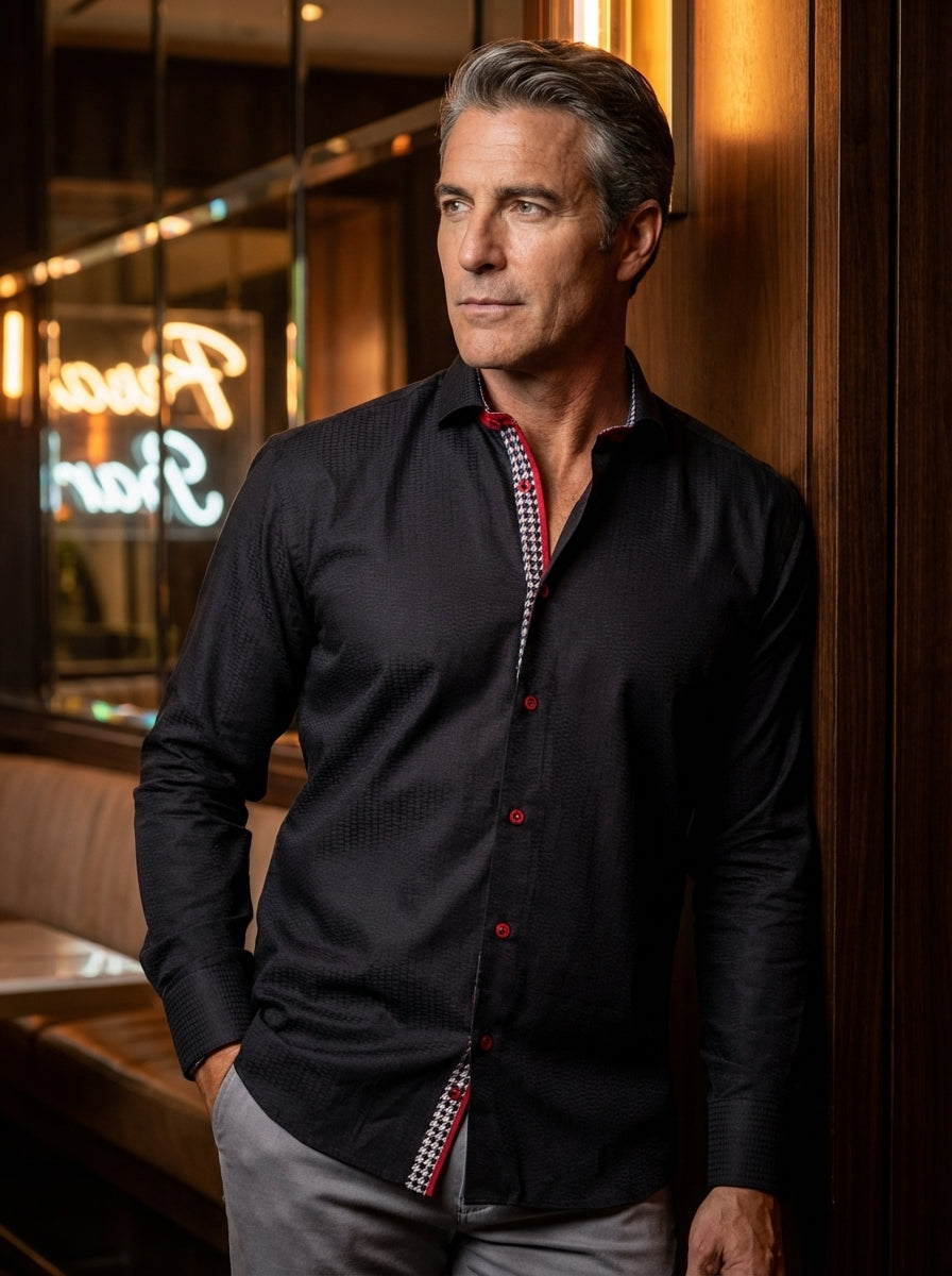 This sophisticated black long-sleeve button-down shirt features a subtle textured jacquard weave and striking red contrast detailing. The inner placket displays a bold geometric pattern, complemented by vibrant red buttons and interior collar trim, creati