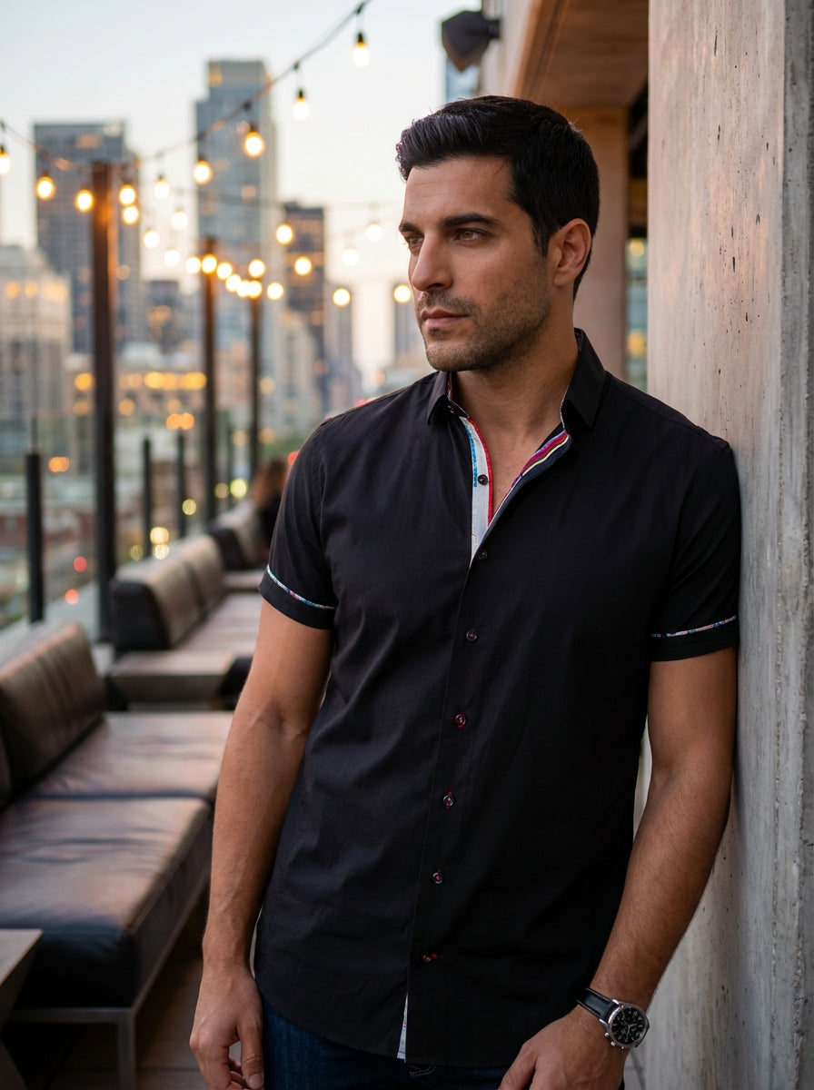 A sophisticated short-sleeve button-down shirt in premium black fabric. This modern fit garment features vibrant multi-colored interior collar detailing, decorative contrast piping on the sleeves, and stylish accent stitching, making it perfect for transi