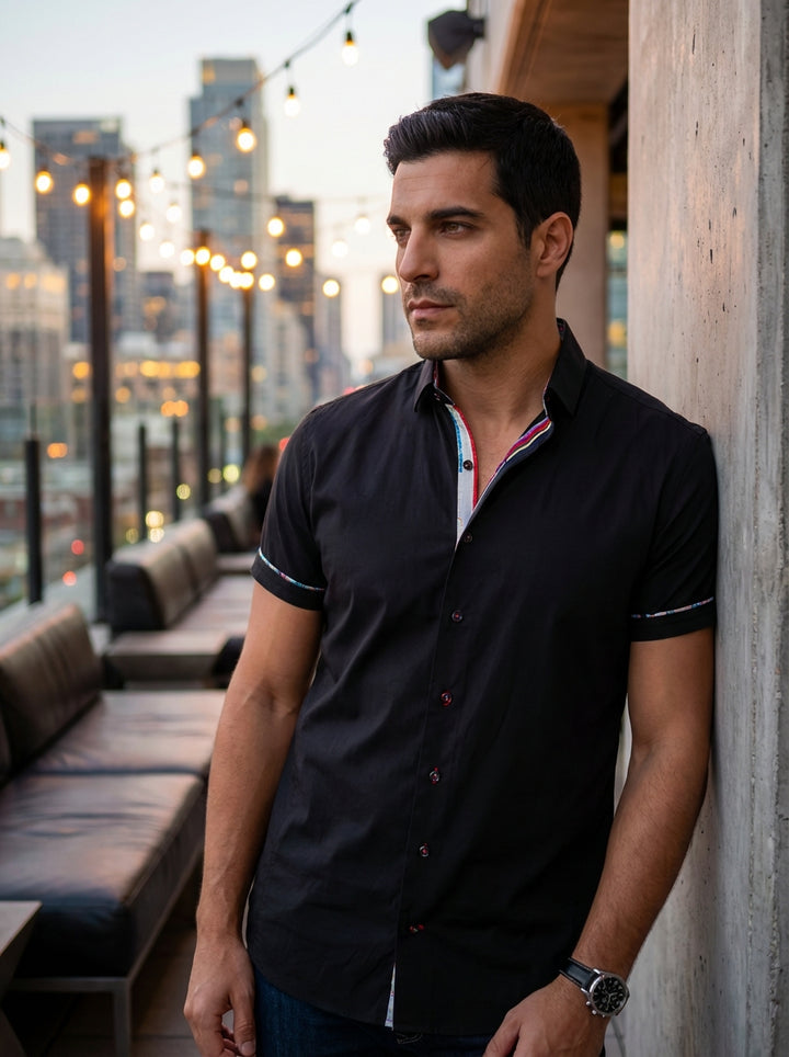 A sophisticated short-sleeve button-down shirt in premium black fabric. This modern fit garment features vibrant multi-colored interior collar detailing, decorative contrast piping on the sleeves, and stylish accent stitching, making it perfect for transi