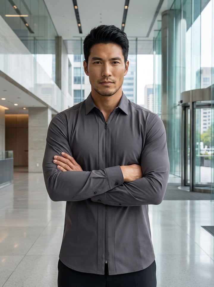 This men's long-sleeve performance shirt in a sleek charcoal grey features a unique full-length front zipper instead of traditional buttons. The technical, stretch-infused fabric provides a modern, tailored fit with a clean-lined aesthetic, finished with 
