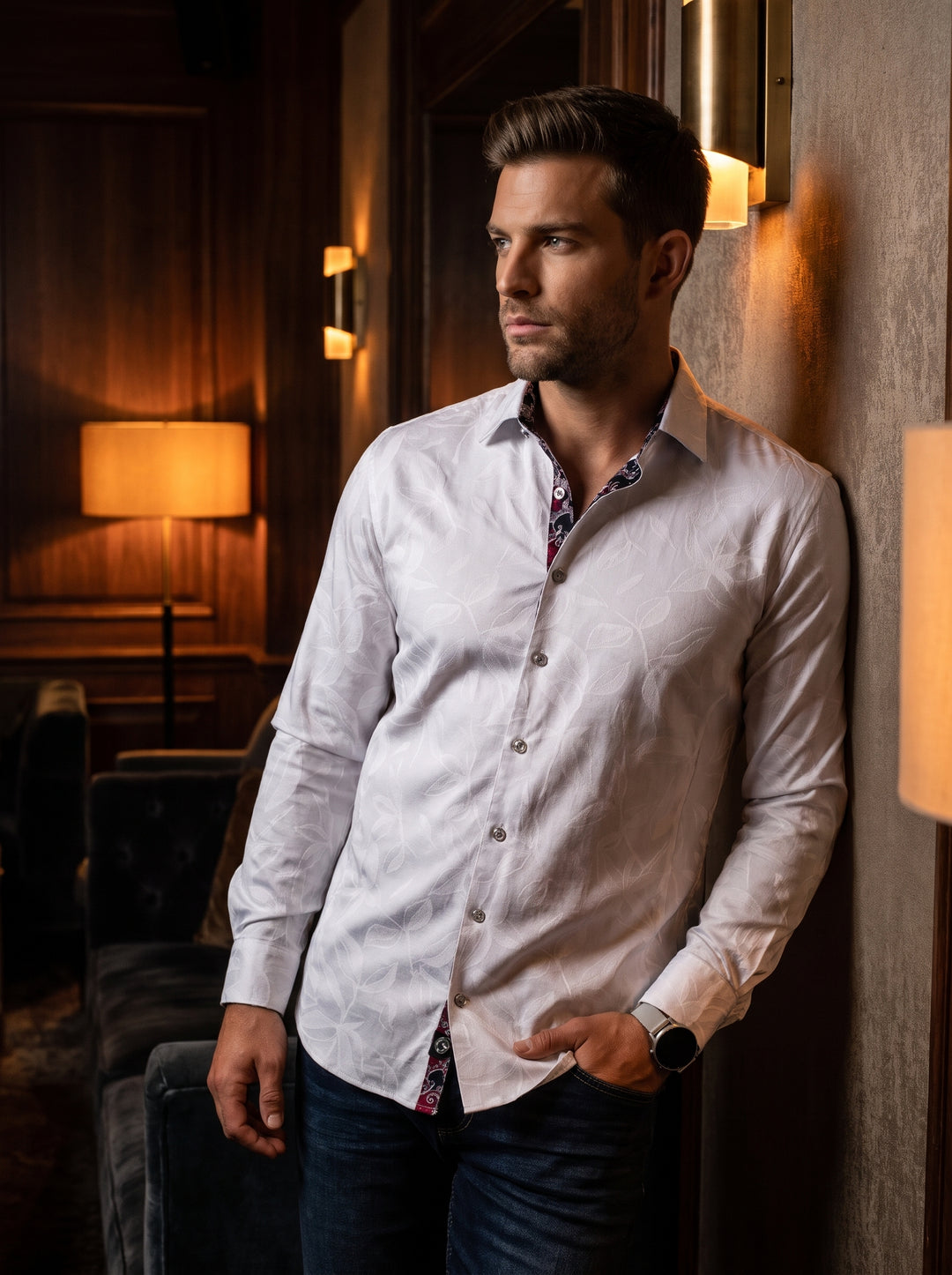 This sophisticated men's long-sleeve dress shirt features a subtle white-on-white leaf jacquard pattern. It is detailed with a contrasting dark floral trim inside the collar and placket, silver-toned buttons, and a tailored fit for a modern, refined aesth