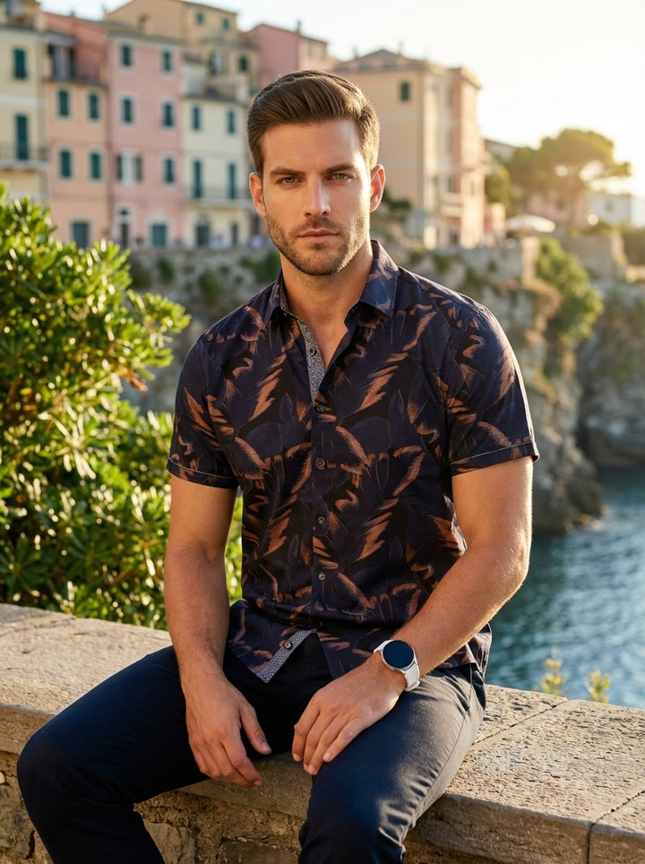 This tailored short-sleeve button-down shirt features a sophisticated dark navy base with a dynamic copper and charcoal abstract leaf print. Crafted with a clean-cut collar and a contrasting inner placket, it offers a refined yet modern aesthetic for casu