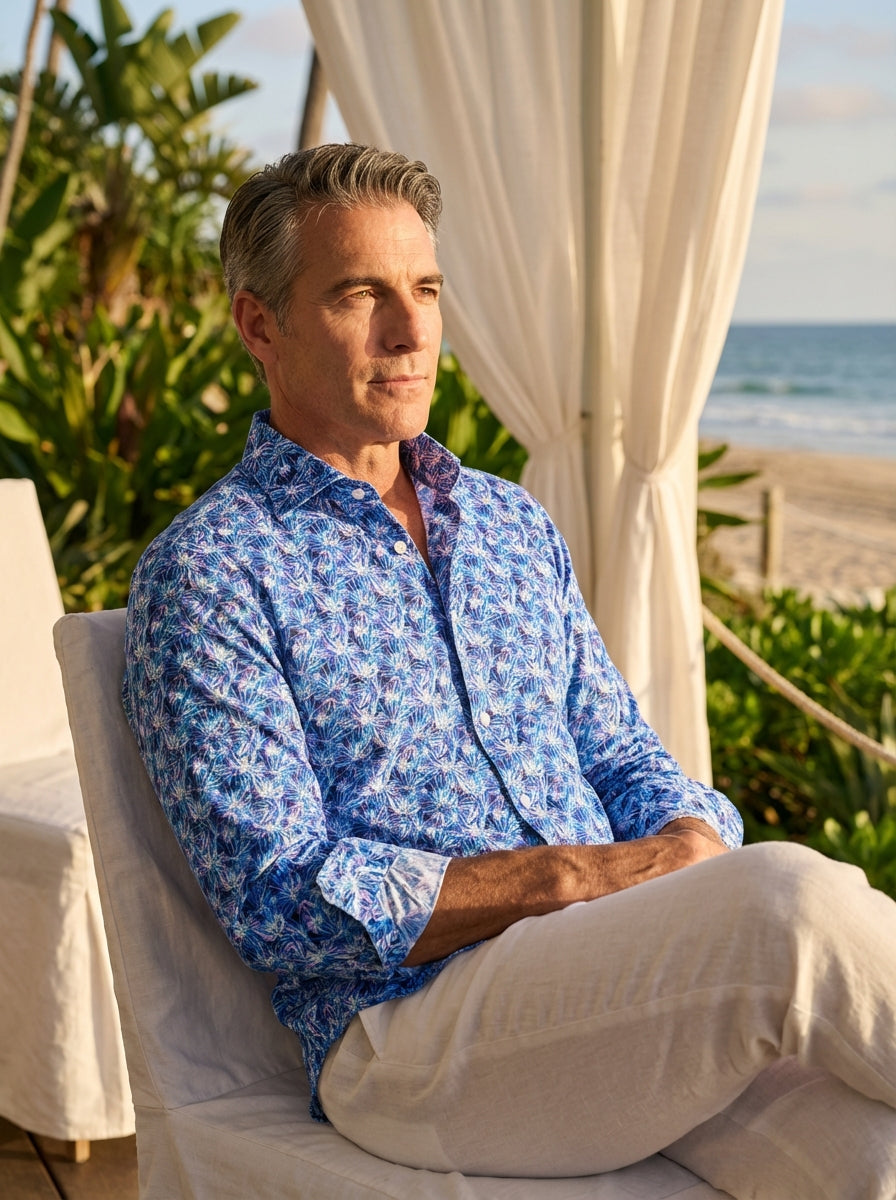 A vibrant long-sleeve button-down shirt by Masutto featuring an intricate all-over tropical palm leaf print in shades of electric blue, purple, and white. This contemporary fit garment includes a spread collar, pearlescent buttons, and adjustable cuffs fo
