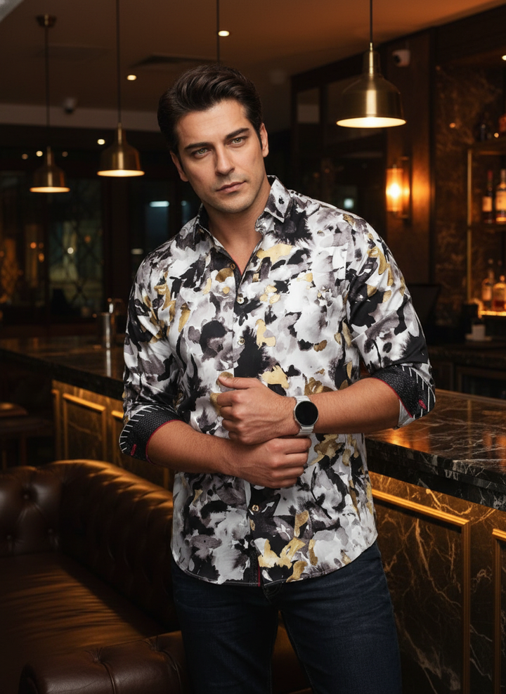 This bold men's button-down shirt features an abstract watercolor floral print in black, grey, and striking gold. Designed with a tailored fit, it includes contrast red interior piping and patterned cuffs for a sophisticated, artistic look perfect for eve